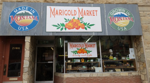 Exterior of Marigold Market, featuring a sign with marigolds and displays of candy and gifts in the window.